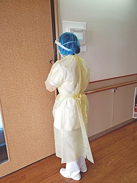 個人防護具を身に付け、感染症病棟の病室に入る看護師の画像